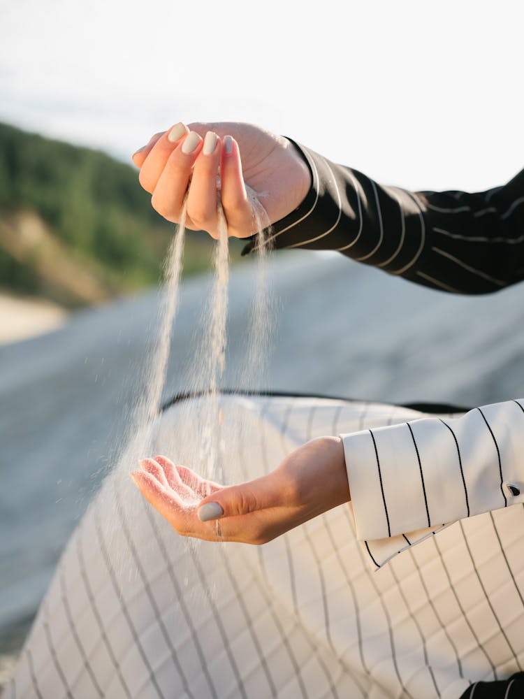 Crop Woman Running Sand Through Hands