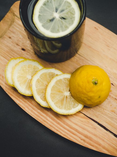Free Close-up of sliced lemon on wood with black mug, perfect for fresh beverage concept. Stock Photo
