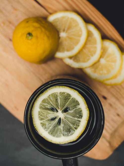 Free Close-up of fresh lemon slices and whole lemon on a wooden board with citrus drink. Stock Photo