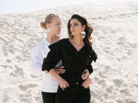 Couple of women with opposite appearance in sand area