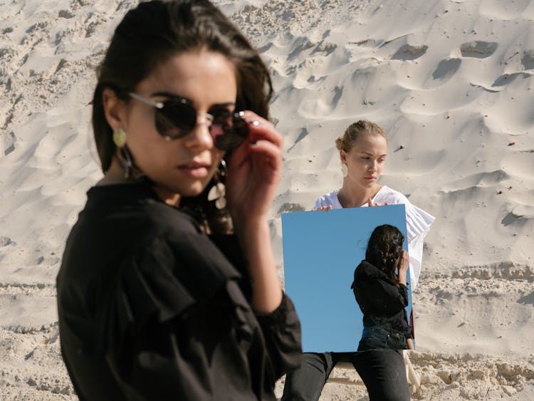 Young Female Rivals With Mirror On Sandy Beach