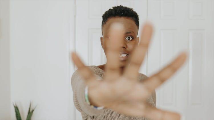 A Woman In Brown Sweater Doing A Stop Hand Gesture