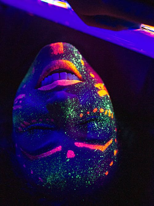 Cheerful woman with colorful luminous painted face