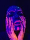 Sensual woman applying neon paint on face with hands