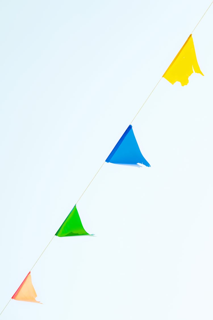 Multicolored String Of Pennant Flags Against Blue Sky