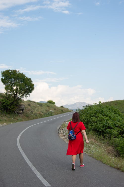 Woman in Red Dress Walking on the Road