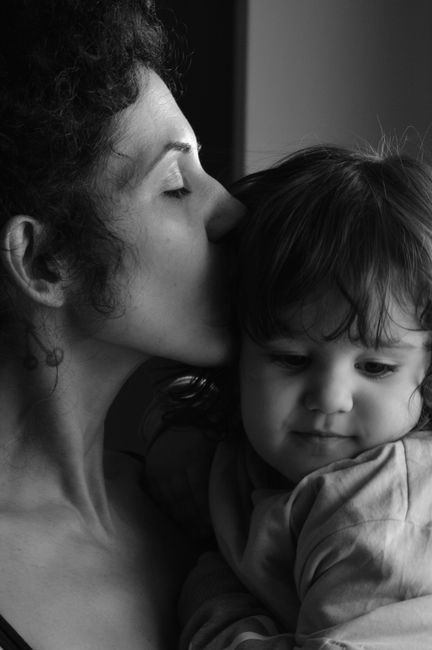 Black and white portrait of a mother kissing her daughter, capturing love and bond.