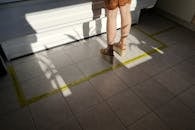 Woman in Brown Skirt and Black Flip Flops Standing on Gray Floor Tiles