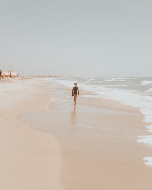 Unrecognizable child walking on wet sandy seashore