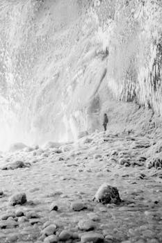 A lone figure explores a majestic ice-covered cave, surrounded by snow and frost.