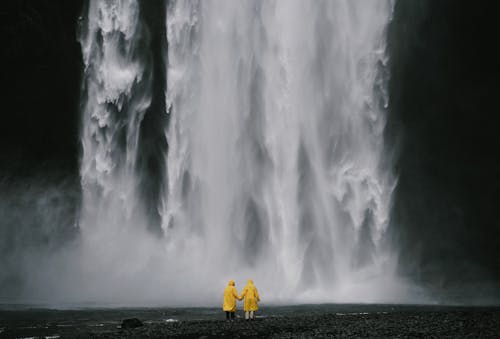 Free Anonymous travelers holding hands against spectacular waterfall Stock Photo