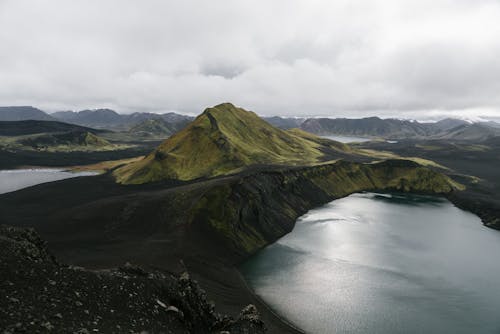 Free Drone view of majestic calm lake surrounded by volcanic mountain ranges in Iceland Stock Photo