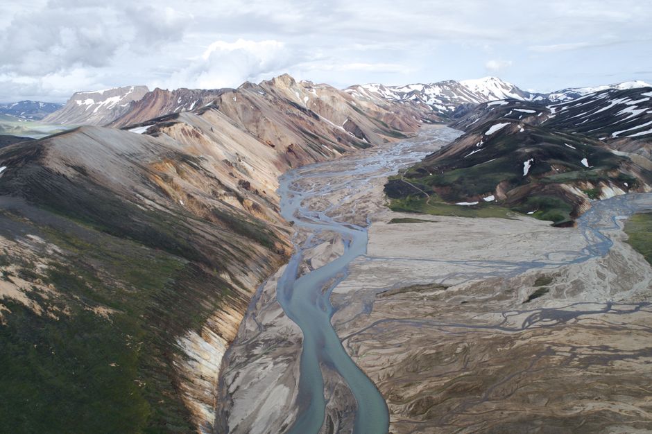 Drone view of scenic rhyolitic mountains in Iceland with muddy river flowing between mountain slopes