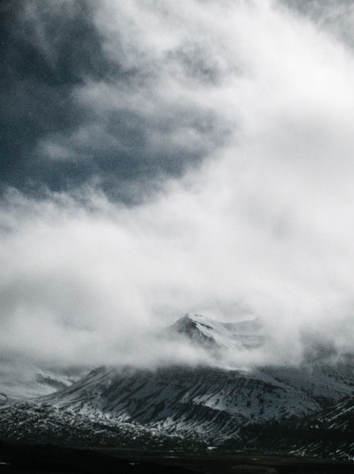 Free Majestic hazy view of snow covered mountain peak wrapped in fluffy white cloud Stock Photo