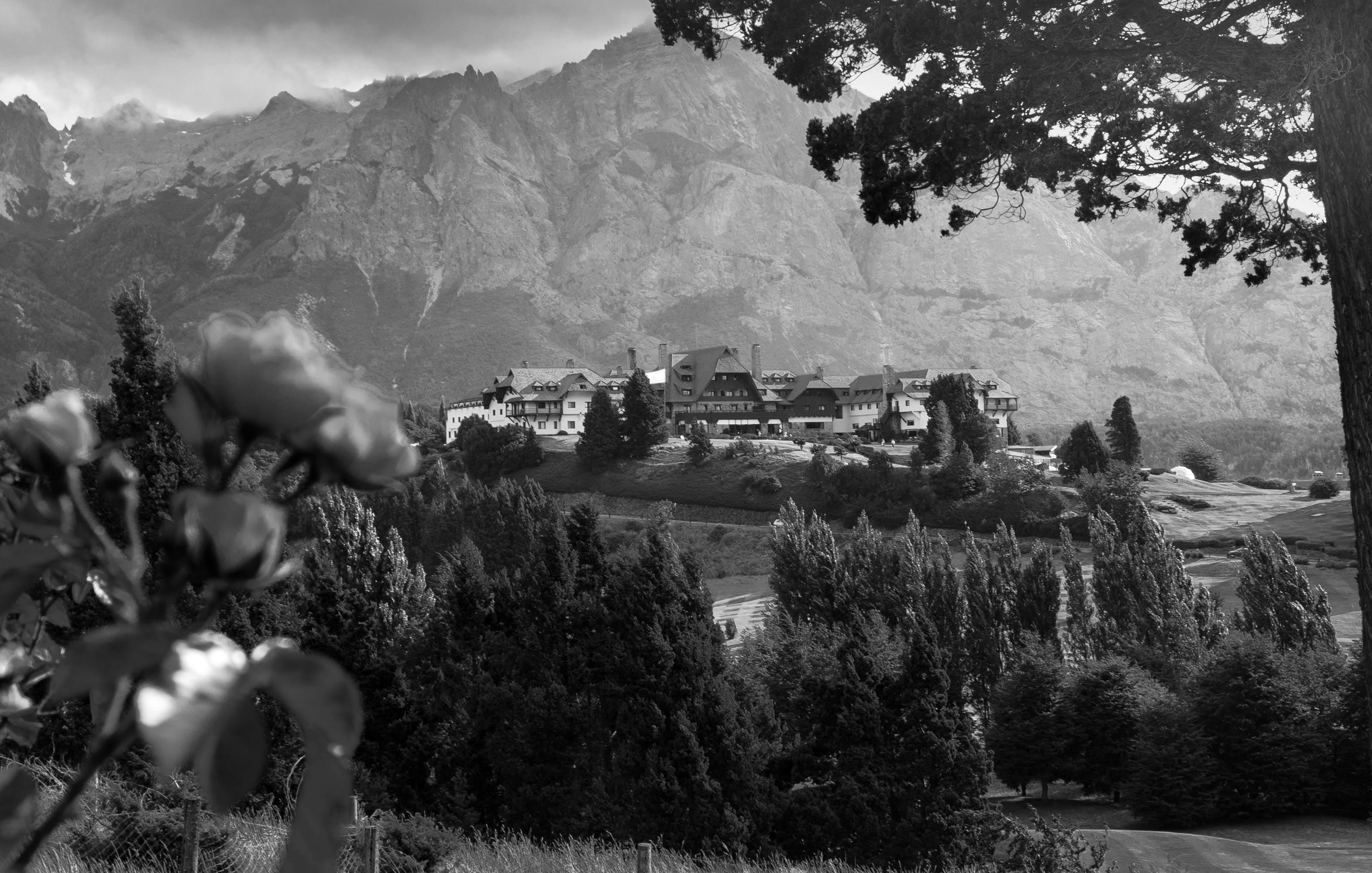 Black and white shot of modern remote village with contemporary decent buildings located amidst majestic mountains and lush abundant greenery