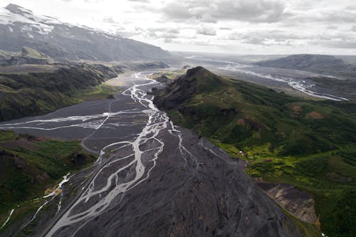 Drone view of rivers in Thorsmork mountain ridge covered with green moss and volcanic ash