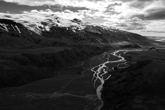 Monochrome aerial view capturing the dramatic landscapes of Iceland with winding rivers and snow-capped peaks.