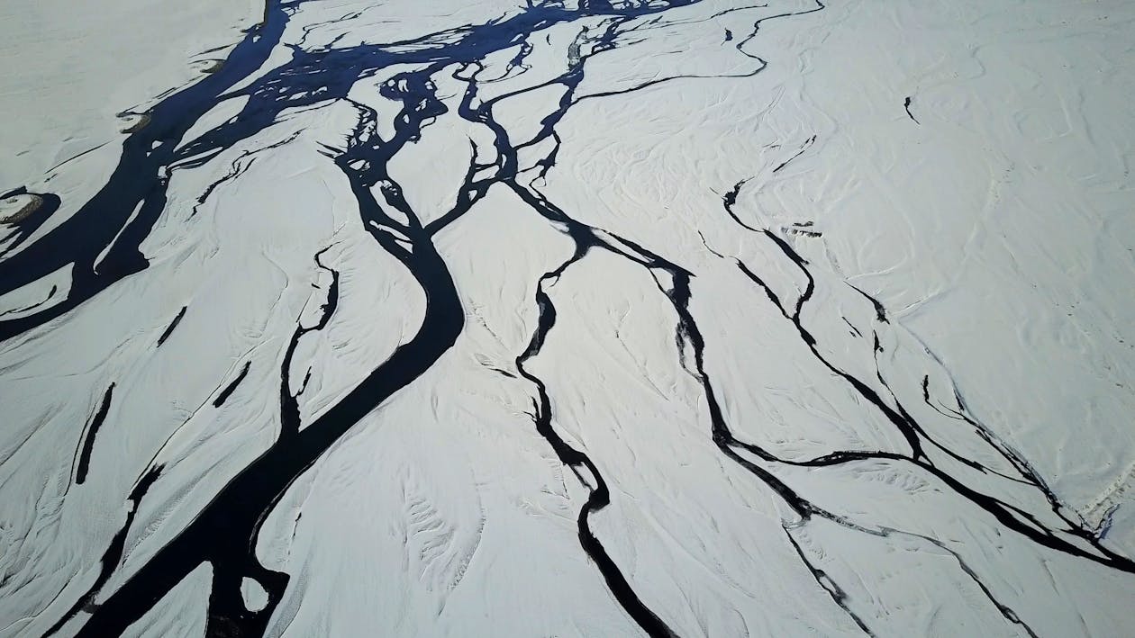 Drone view of snow covered terrain with picturesque glacial river system in winter