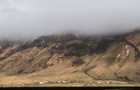 Mountain ridge with tiny village at bottom on cloudy day