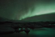 星空下，黑暗的石质地形与惊人的极光、充满活力的绿色发光交相辉映