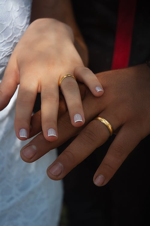 Free High angle crop faceless multiethnic couple wearing classy wedding outfits demonstrating golden rings on ring fingers Stock Photo