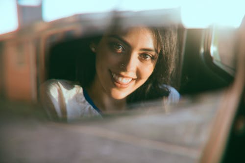 Free Reflection of cheerful woman in car window Stock Photo