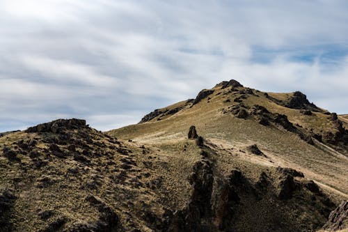 Mountainous landscape of high rocky rough steep peak under cloudy sky at daytime