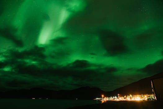 夜晚，壮丽的北极光在宁静的沿海小镇上空熠熠生辉