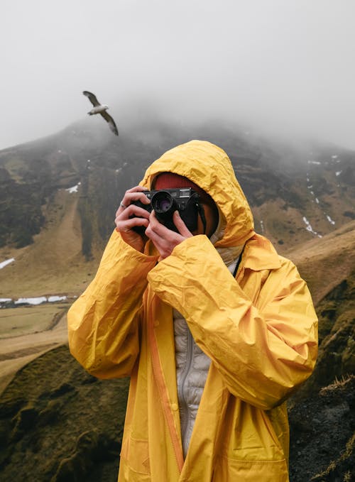 Crop unrecognizable tourist taking photo with photo camera in mist