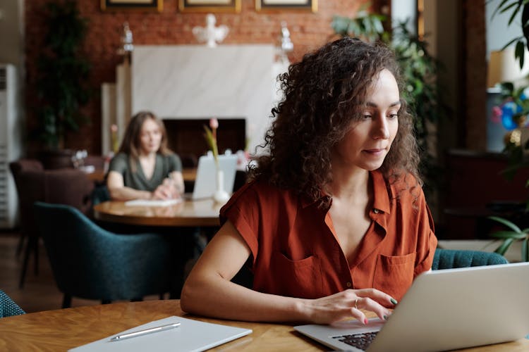 A Woman Seated Is Scrolling On Her Laptop