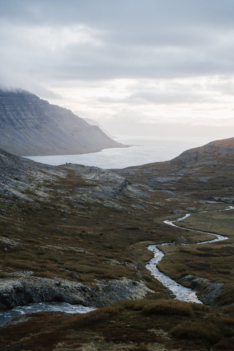 Ocean Surrounded By Mountains And River Tributaries Under Cloudy Sky