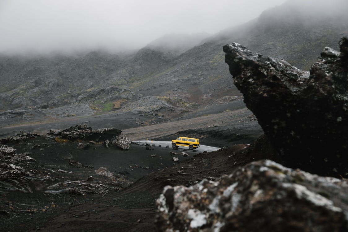 Car driving on road between ridge under overcast sky