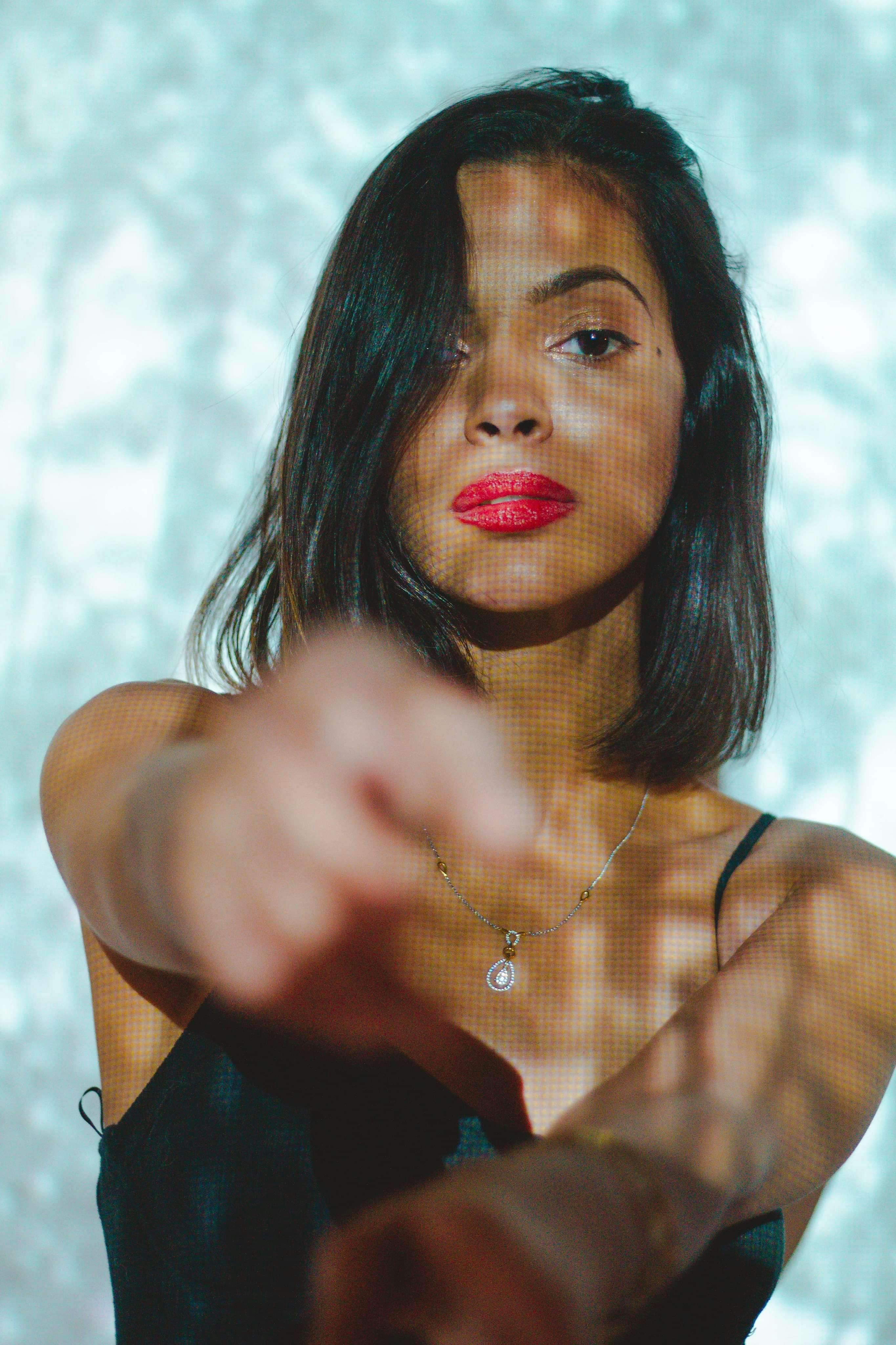 Young ethnic female with makeup and projection on body pointing and looking at camera