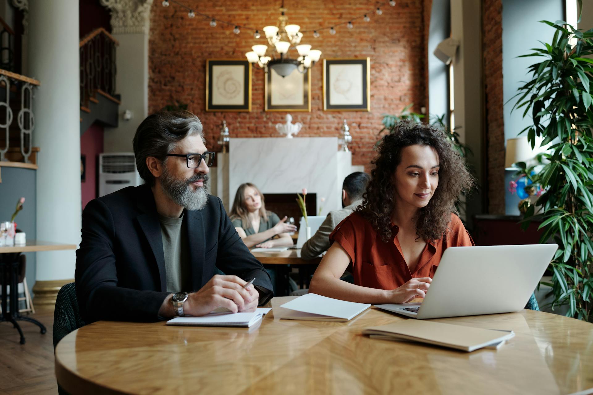 Business professionals collaborating over laptops and notes in a stylish workspace.