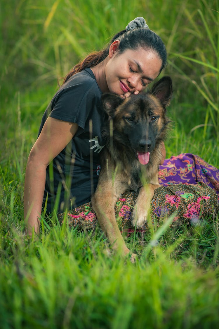 Calm Woman Hugging Dog Sitting On Grass