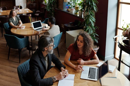 Professionals engaging in a collaborative meeting in a cozy café setting, discussing business projects.