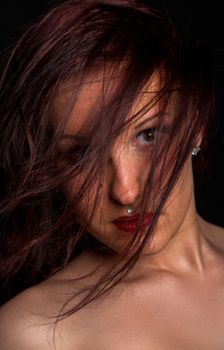 Close-up portrait of a woman with dark hair and captivating expression against a black background.