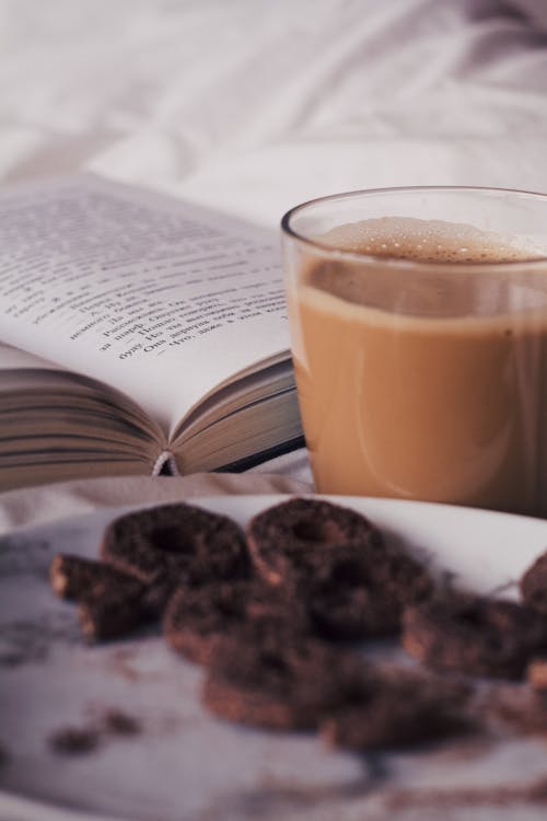 Cup of coffee with plate of cookies near book