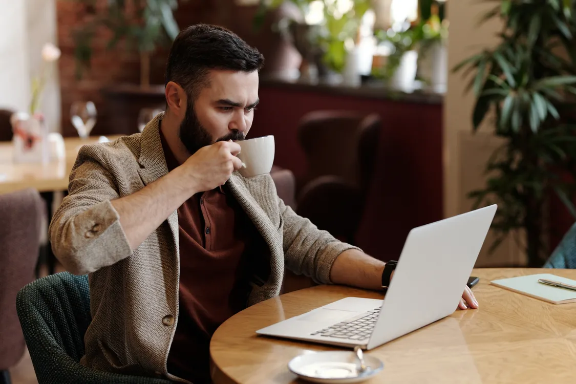 Muškarac radi na laptopu u kafiću uz kavu — planiranje i postavljanje lokalnog SEO-a i online prisutnosti obrta