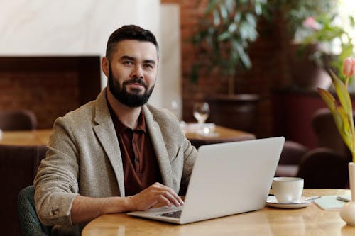 Free Man Sitting on a table with Laptop and Cup of Coffee Stock Photo