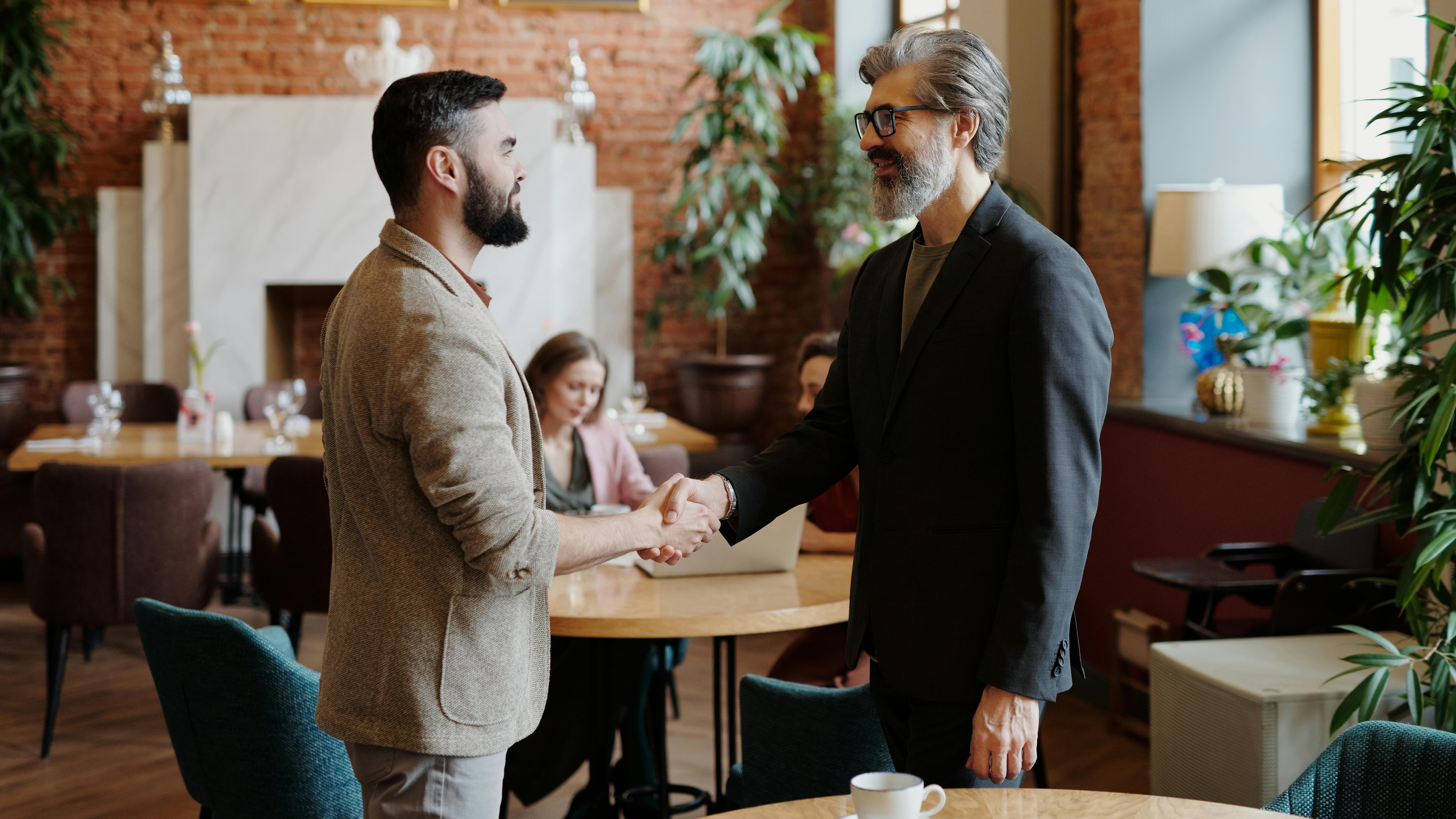 bearded men in brown and gray suit doing handshake