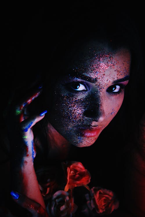 From above of young lady with glowing makeup and colorful arms with bunch of roses