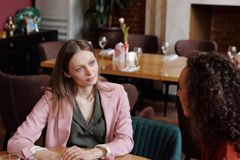 Two women having a thoughtful conversation in a cozy café setting, discussing over coffee.
