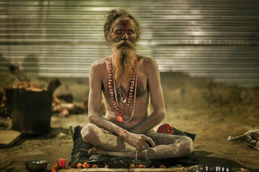 A holy sadhu meditates cross-legged with closed eyes at Kumbh Mela, India.