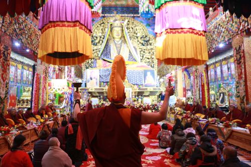 Free Back view of local monk in traditional clothes standing in Buddhist temple with people praying on floor Stock Photo