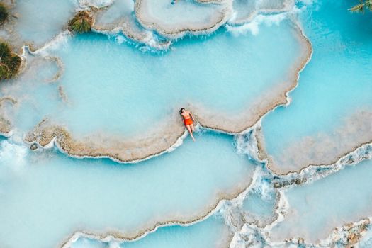 Relaxing woman in Saturnia's stunning turquoise hot springs, Tuscany.
