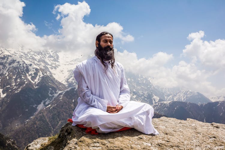 A Man In White Thobe Meditating On The Mountain Top