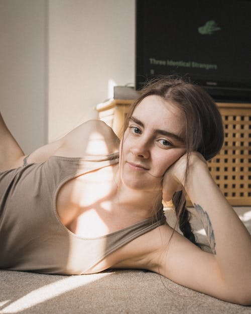 Calm female wearing comfy clothes relaxing on floor in cozy room in rays of sun