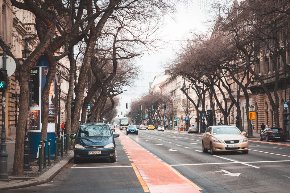 A Bolt ride-hailing taxi car driving on a street in Budapest, Hungary, with city buildings in the background.