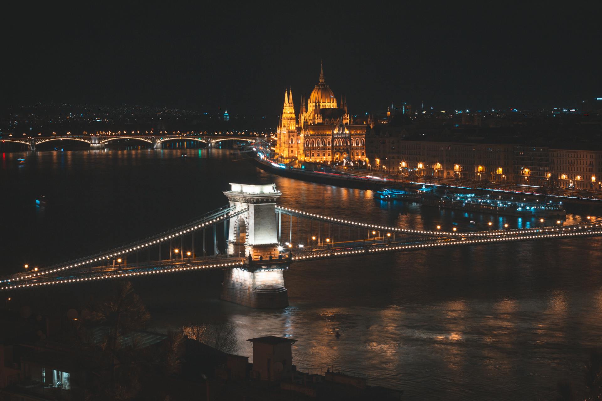 Illuminated Chain Bridge and Hungarian Parliament with river at night in Budapest.